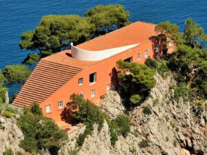 Terracotta brick building on the Italian cliffside. Stairs lead up the back of the building to a runway for a fashion show.