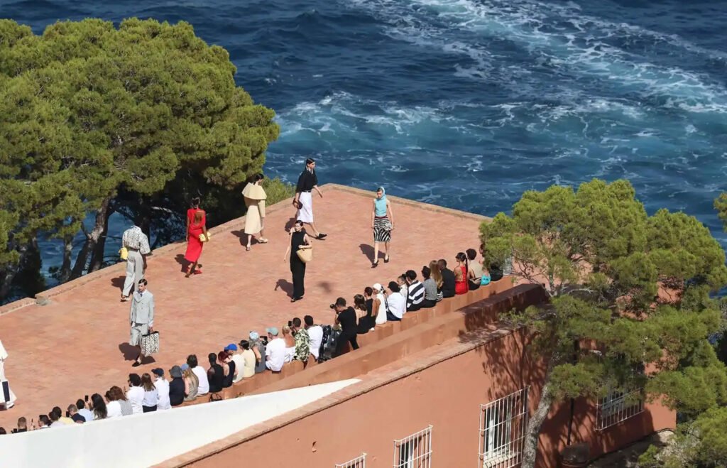 Jacquemus fashion show in Capri. Models walk on the roof of a terracotta building next to the ocean.