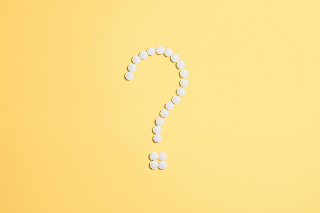 Question mark made out of white spheres on a pale yellow background.