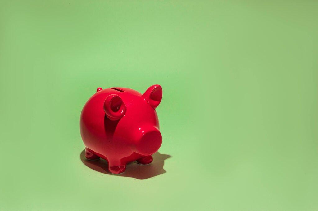 A red piggy bank on pastel green background.
