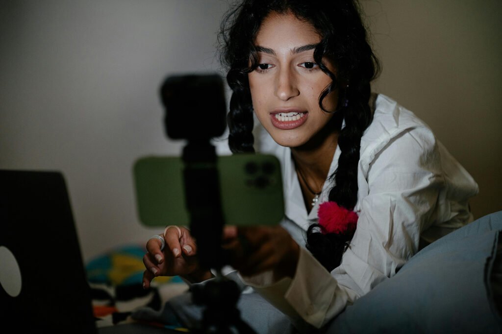 A woman with plaited hair shooting content with a green IPhone.