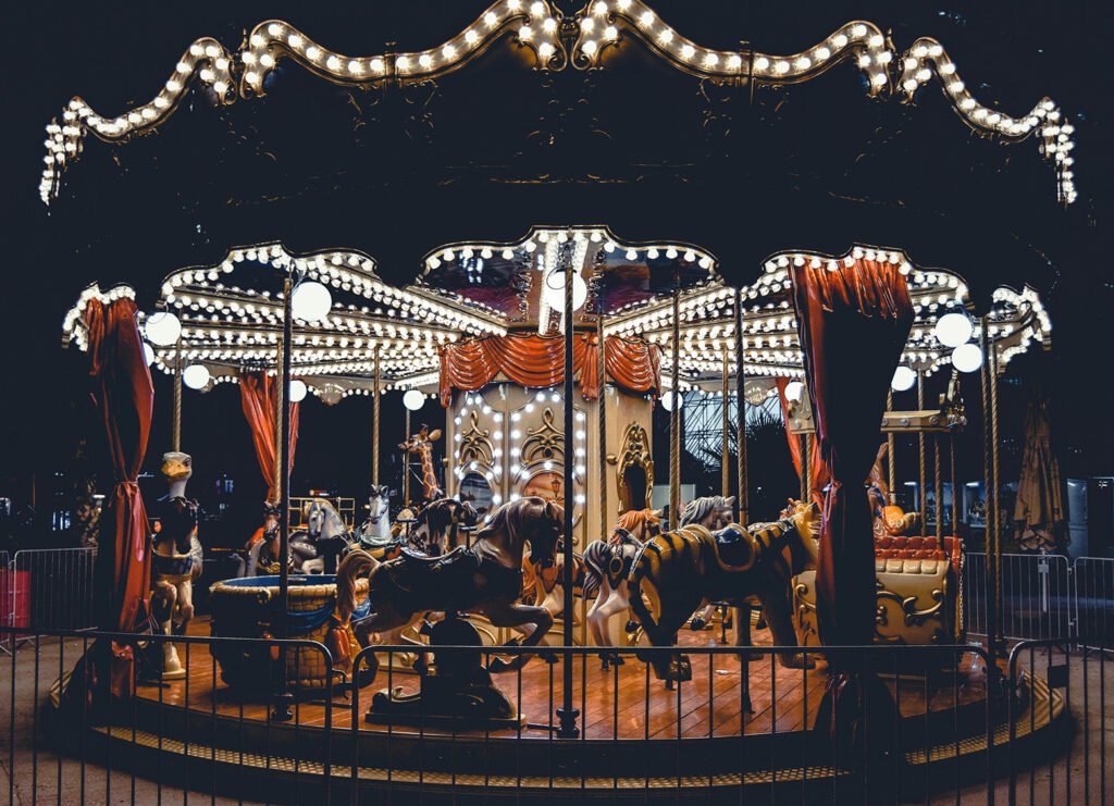 Carousel fairground ride with horses and lights.
