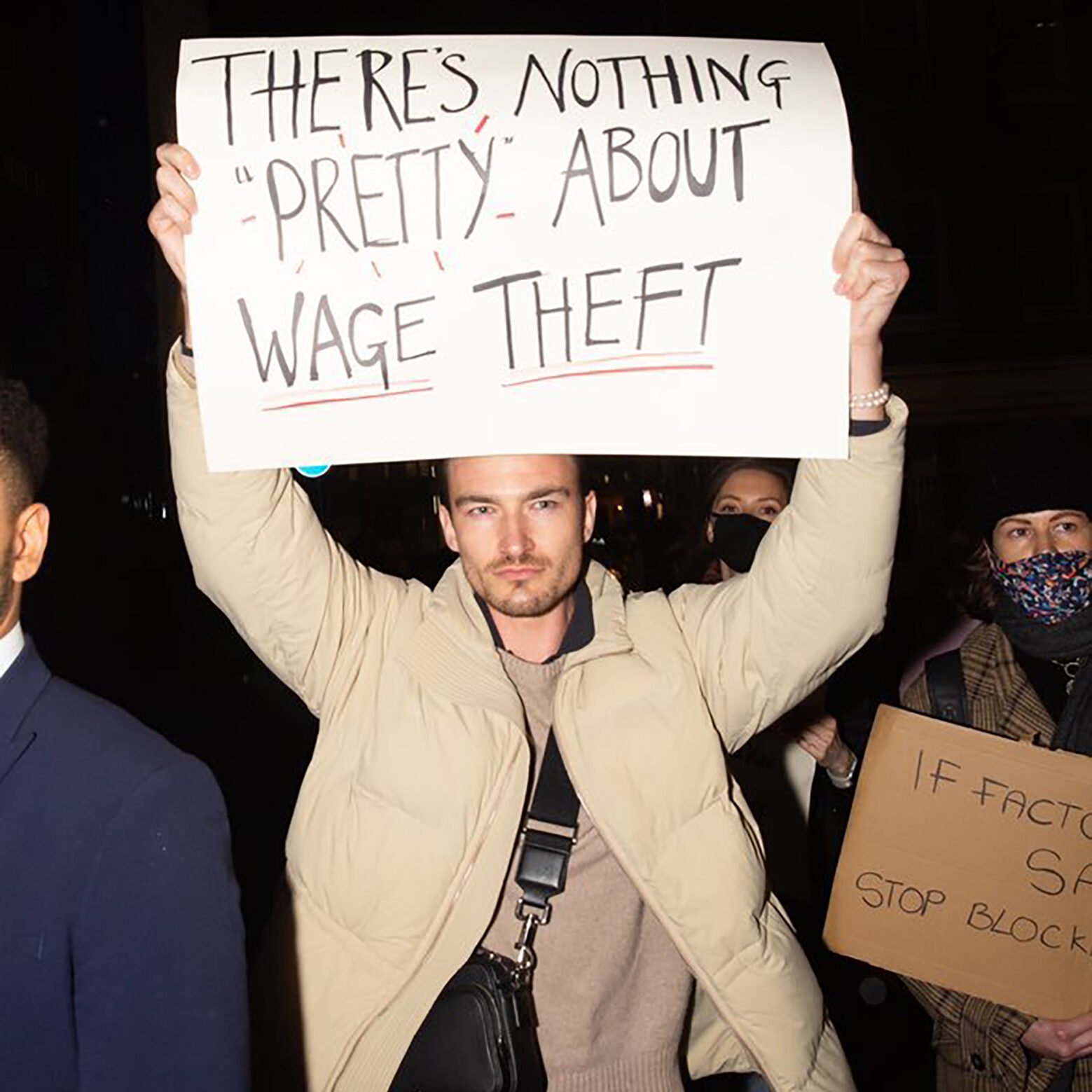 Love island star Brett Staniland protesting with a banner that reads There's nothing pretty about wage theft.